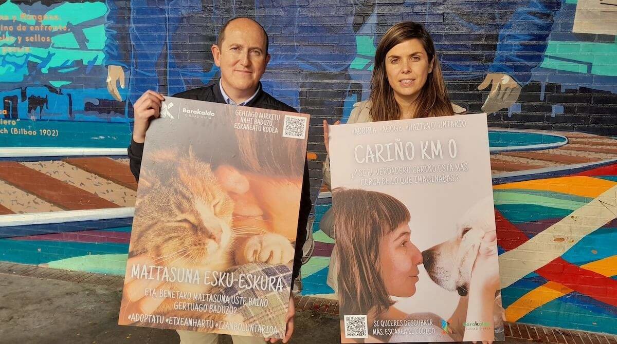Foto de Carlos Fernández y Alba Delgado con las imágenes de la campaña de fomento de adopción de animales.